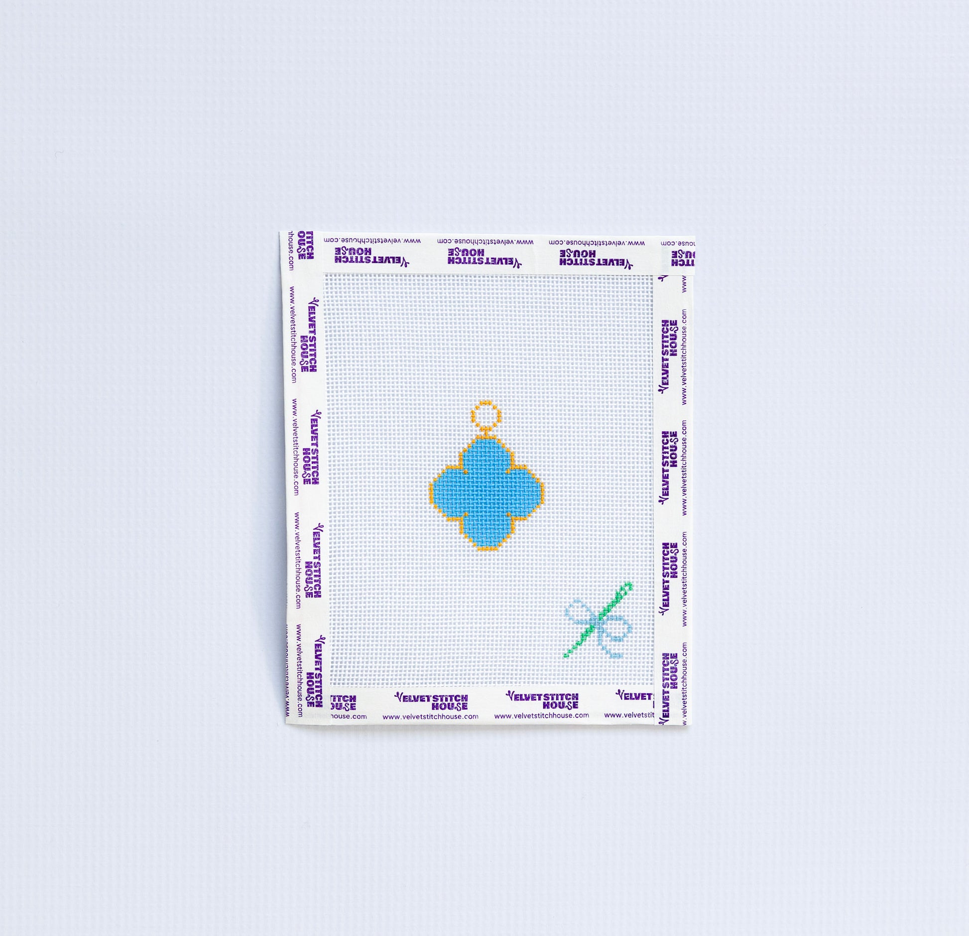 Needlepoint pattern with blue van cleef charm on white background