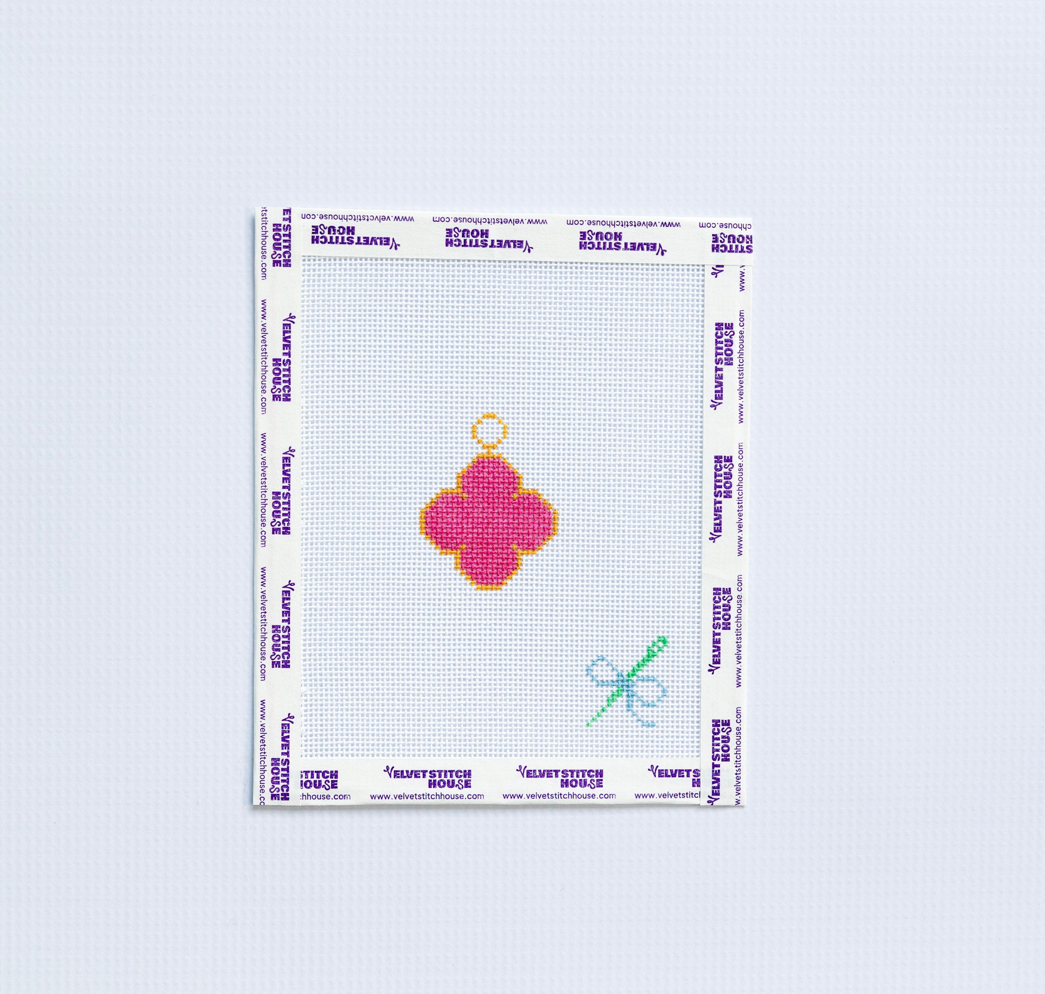 Needlepoint pattern with a pink van cleef design on a white fabric swatch.