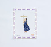 Needlepoint pattern of a woman in a blue dress holding an umbrella on a white background.