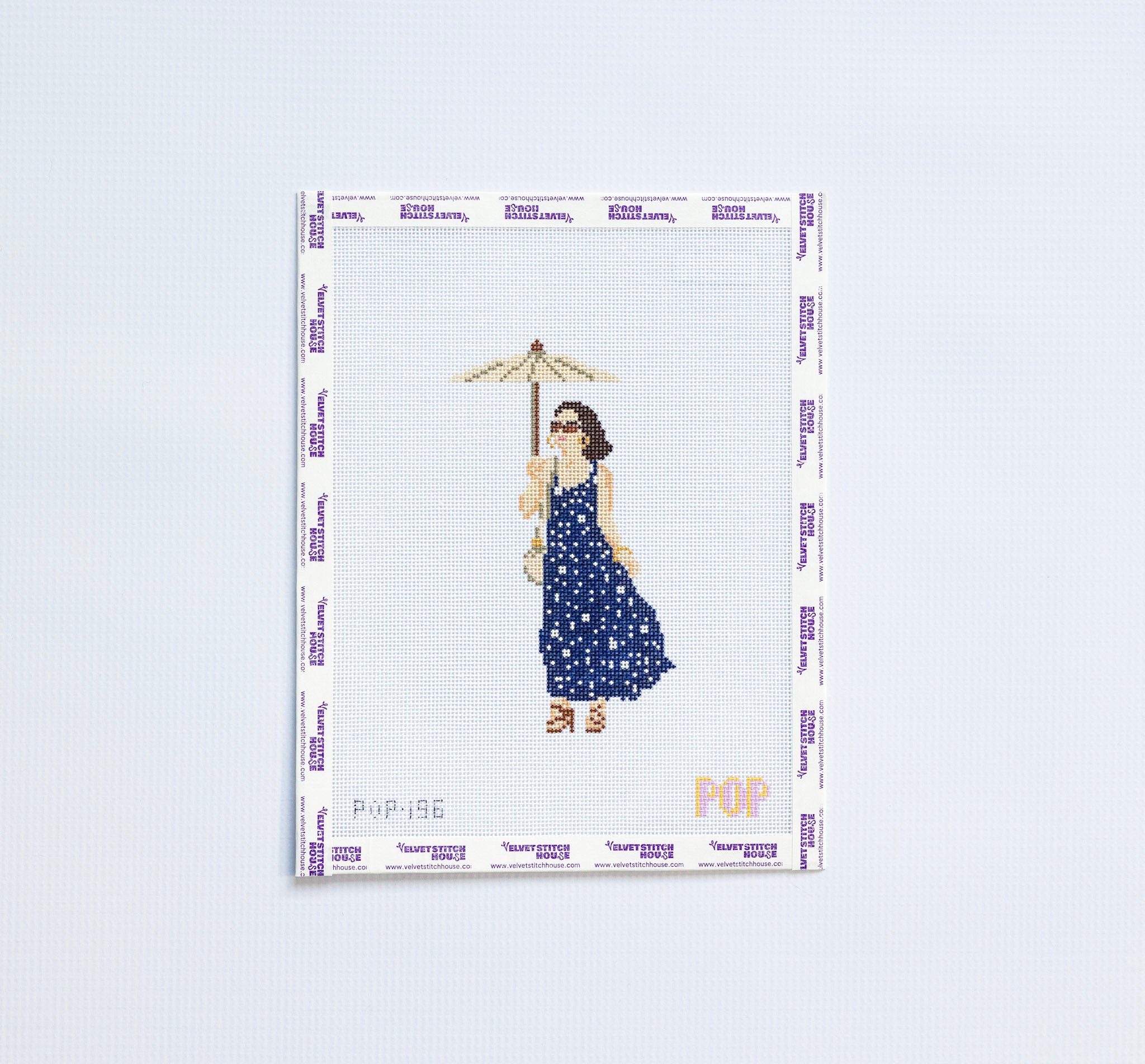 Needlepoint pattern of a woman in a blue dress holding an umbrella on a white background.