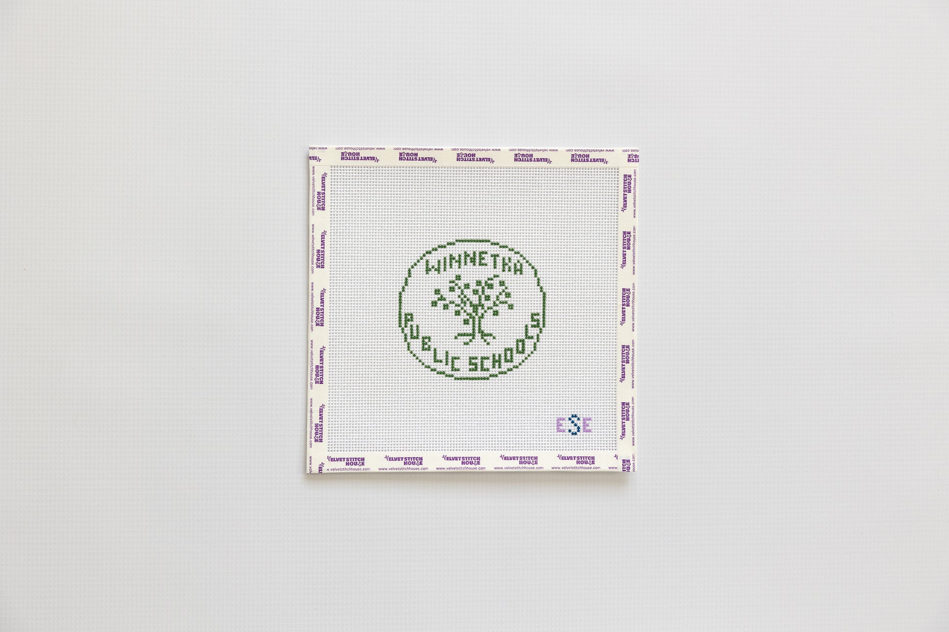 Needlepoint round design with 'Winnetka Public School' logo on a white background