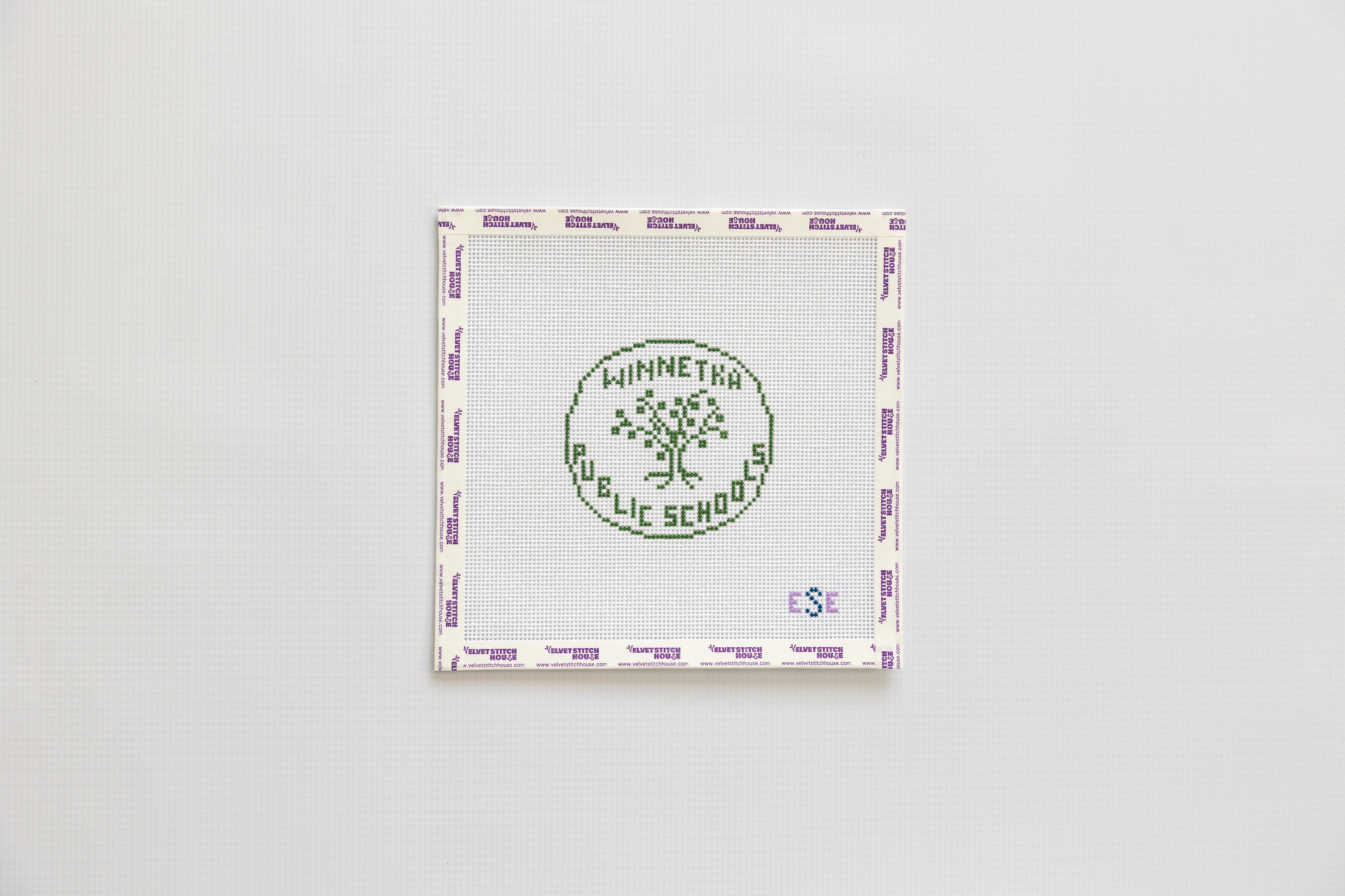 Needlepoint round design with 'Winnetka Public School' logo on a white background