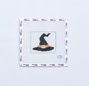 Needlepoint pattern of a black witch's hat on fabric with a white border.
