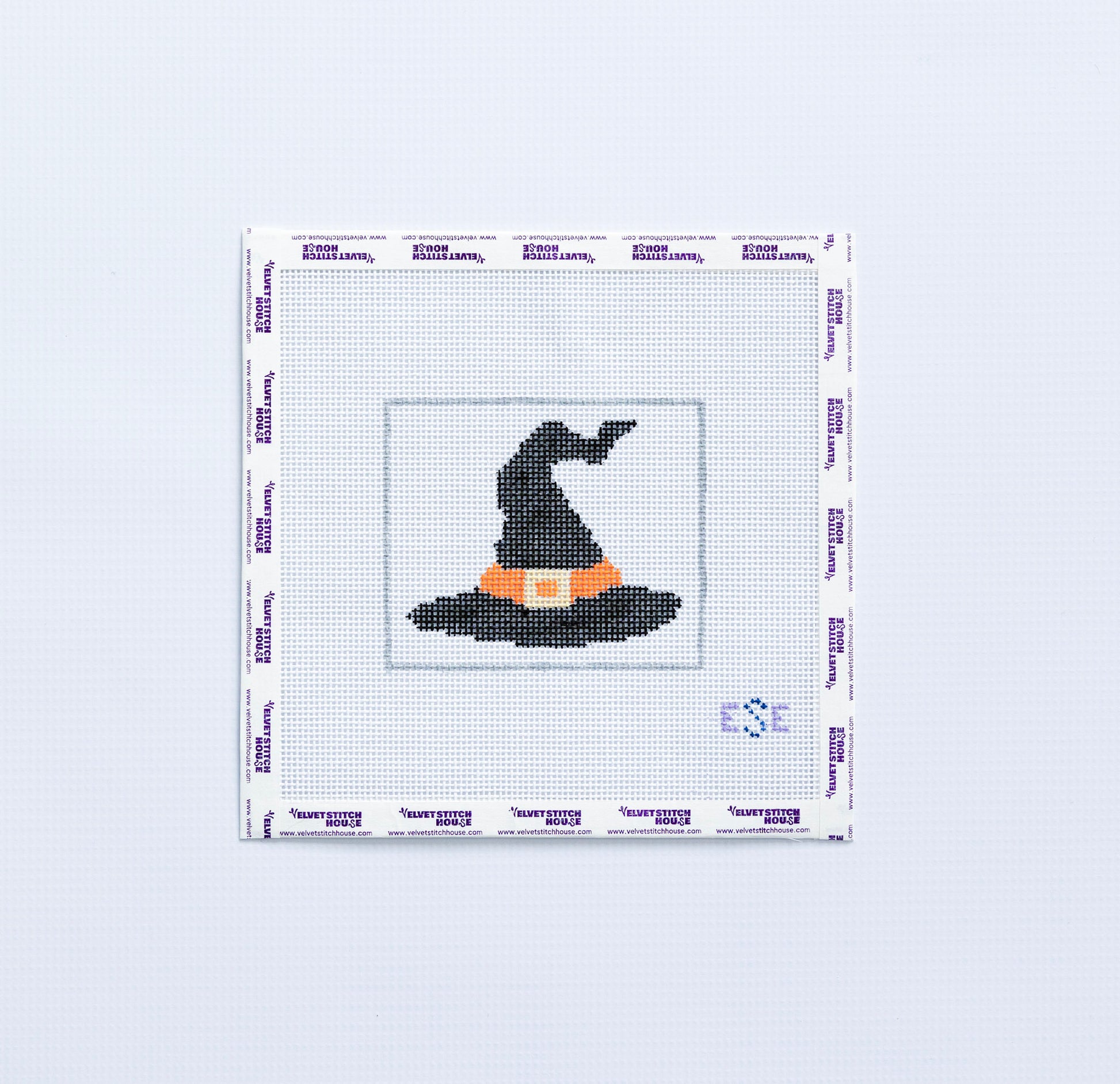 Needlepoint pattern of a black witch's hat on fabric with a white border.
