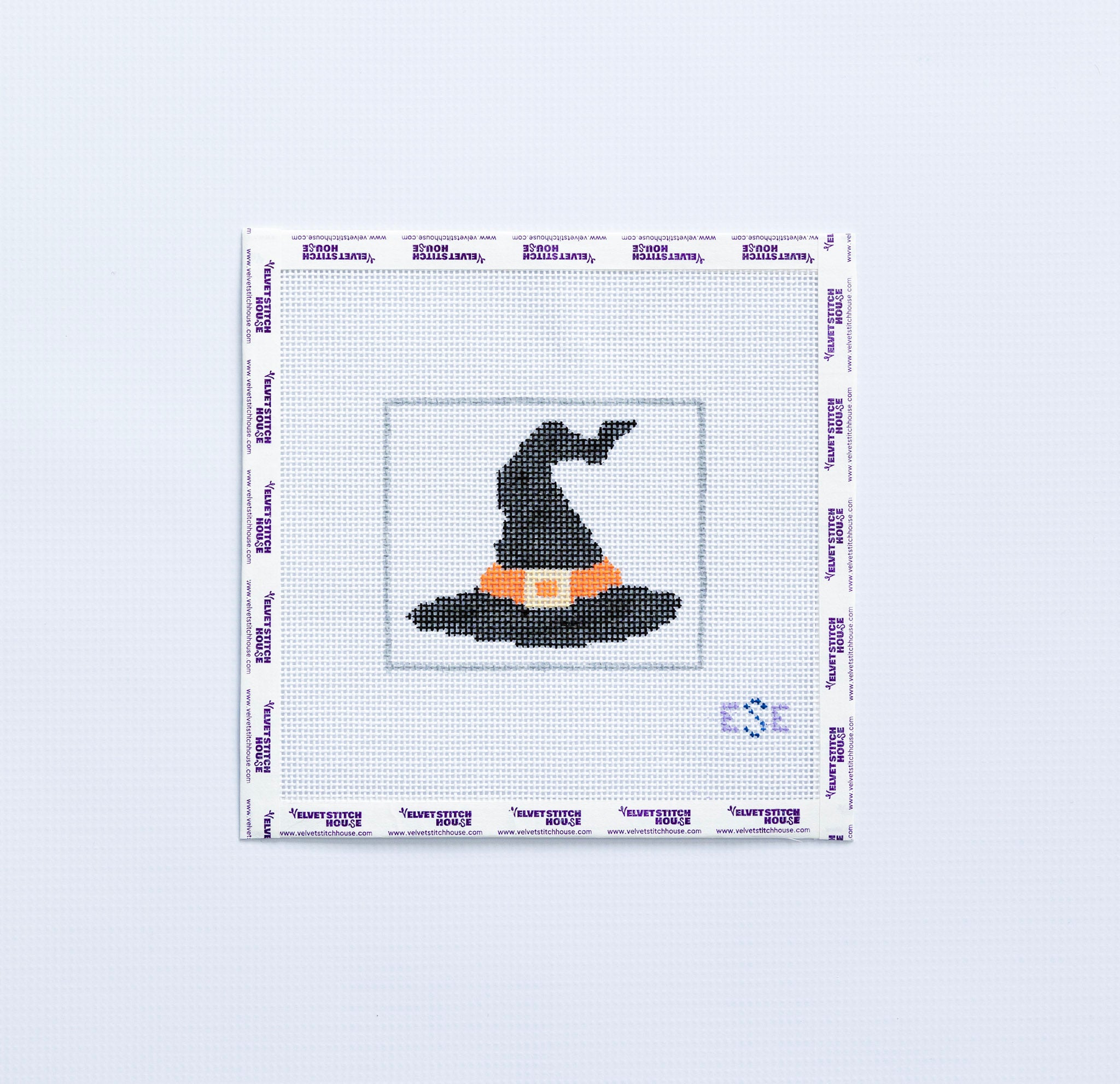 Needlepoint pattern of a black witch's hat on fabric with a white border.