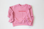Pink sweatshirt with 'WORK IN PROGRESS' text