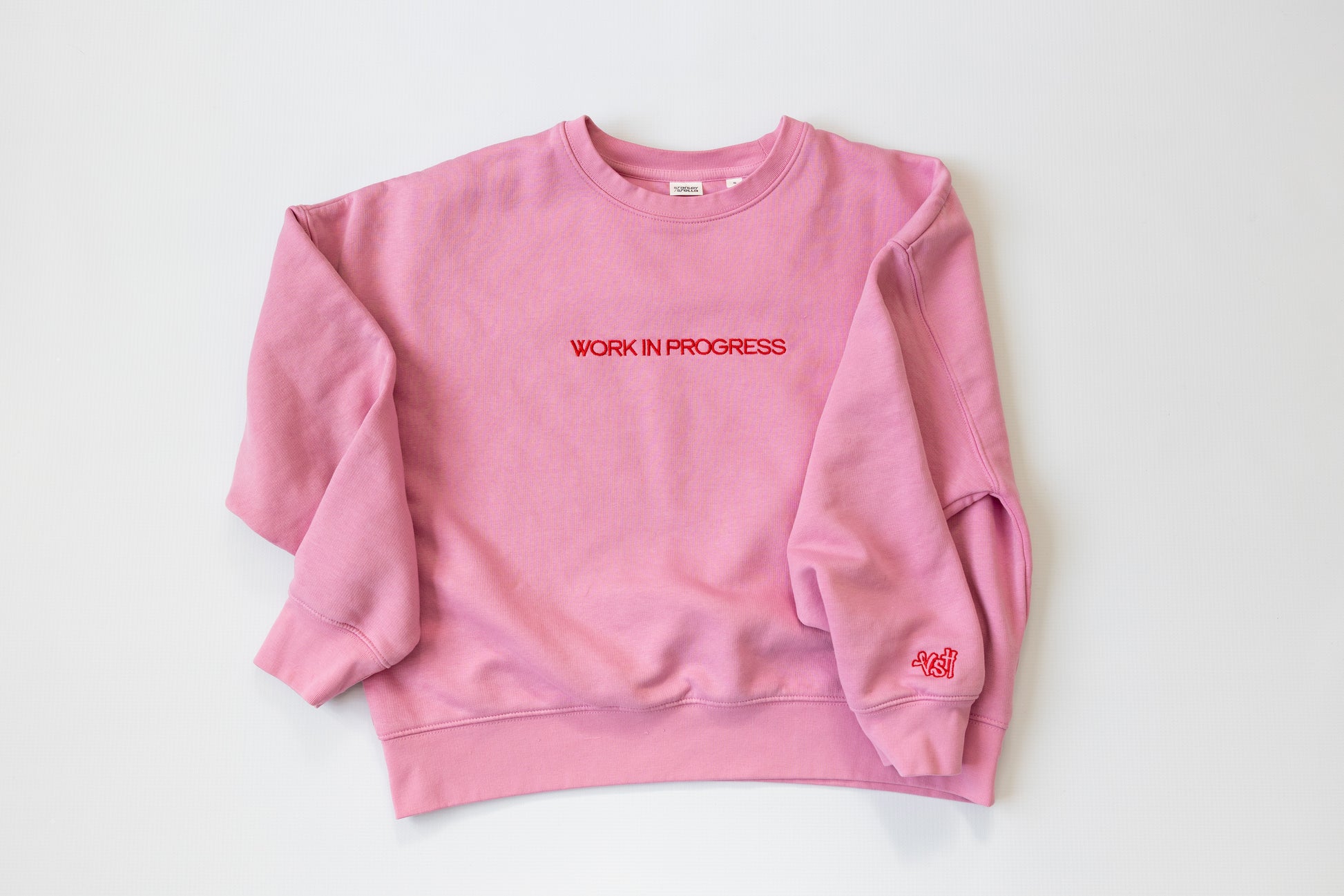 Pink sweatshirt with 'WORK IN PROGRESS' text