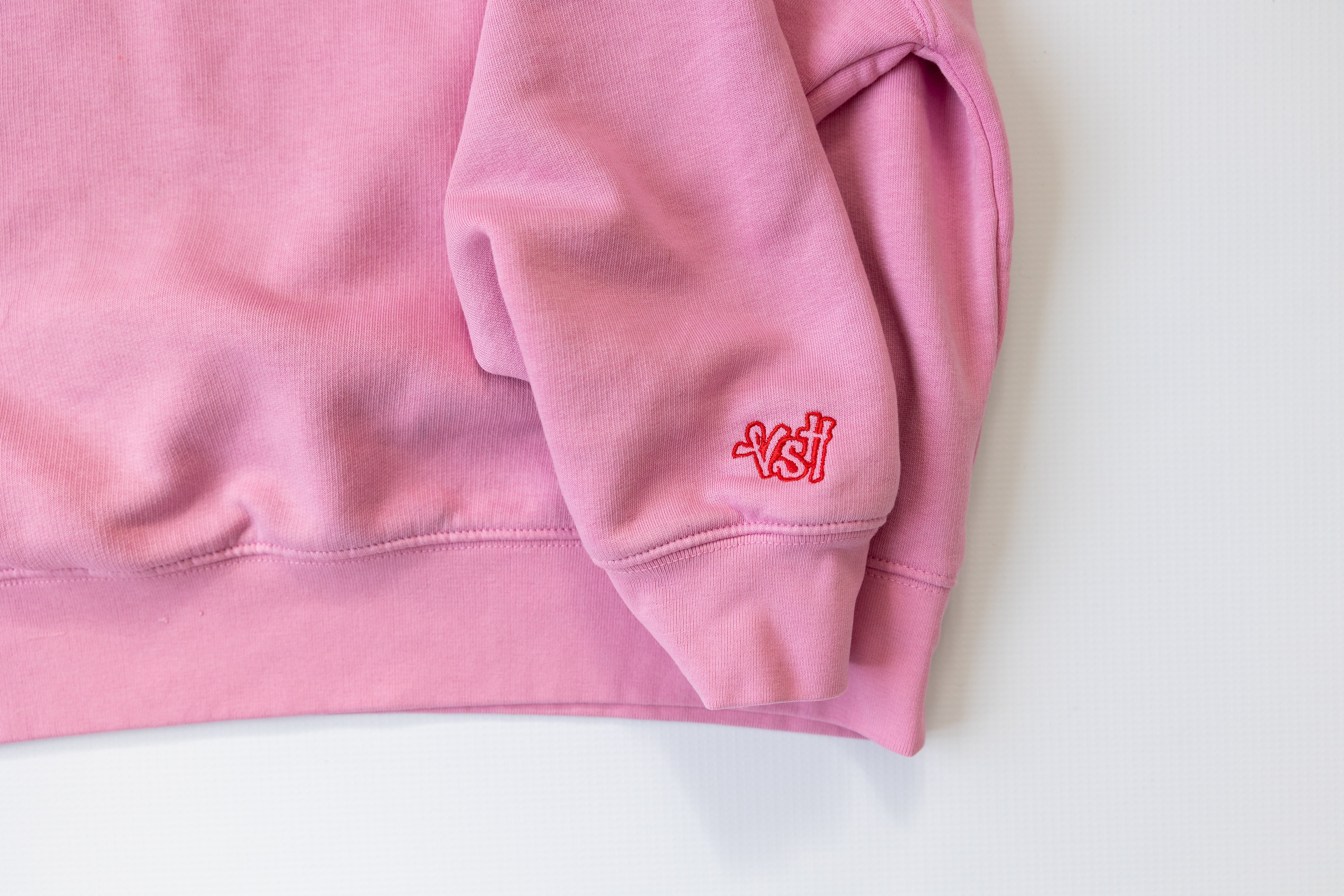 Pink sweatshirt with a red logo on a white background