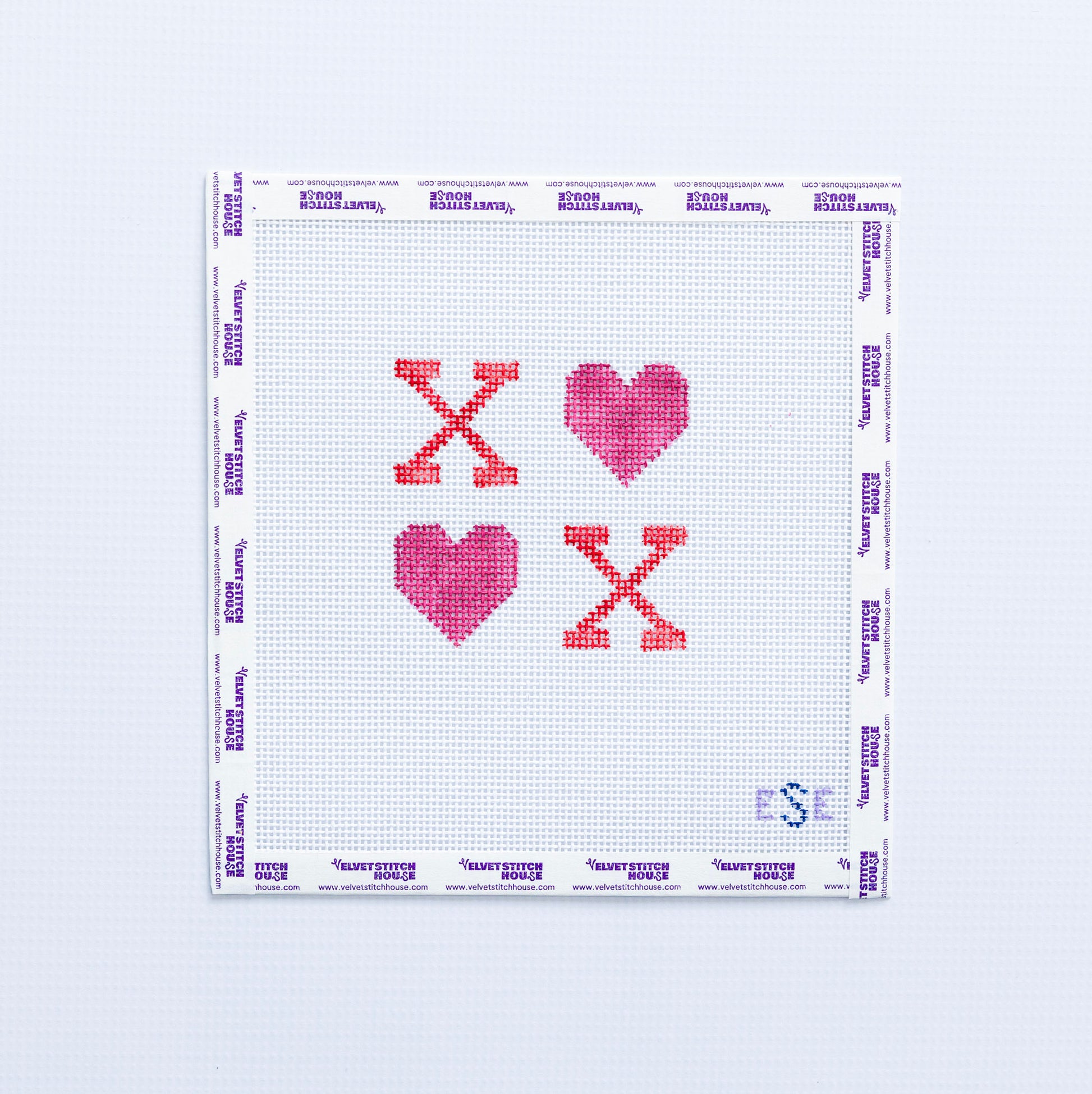 Needlepoint pattern with hearts in pink and red text with 'XO' on a white fabric background