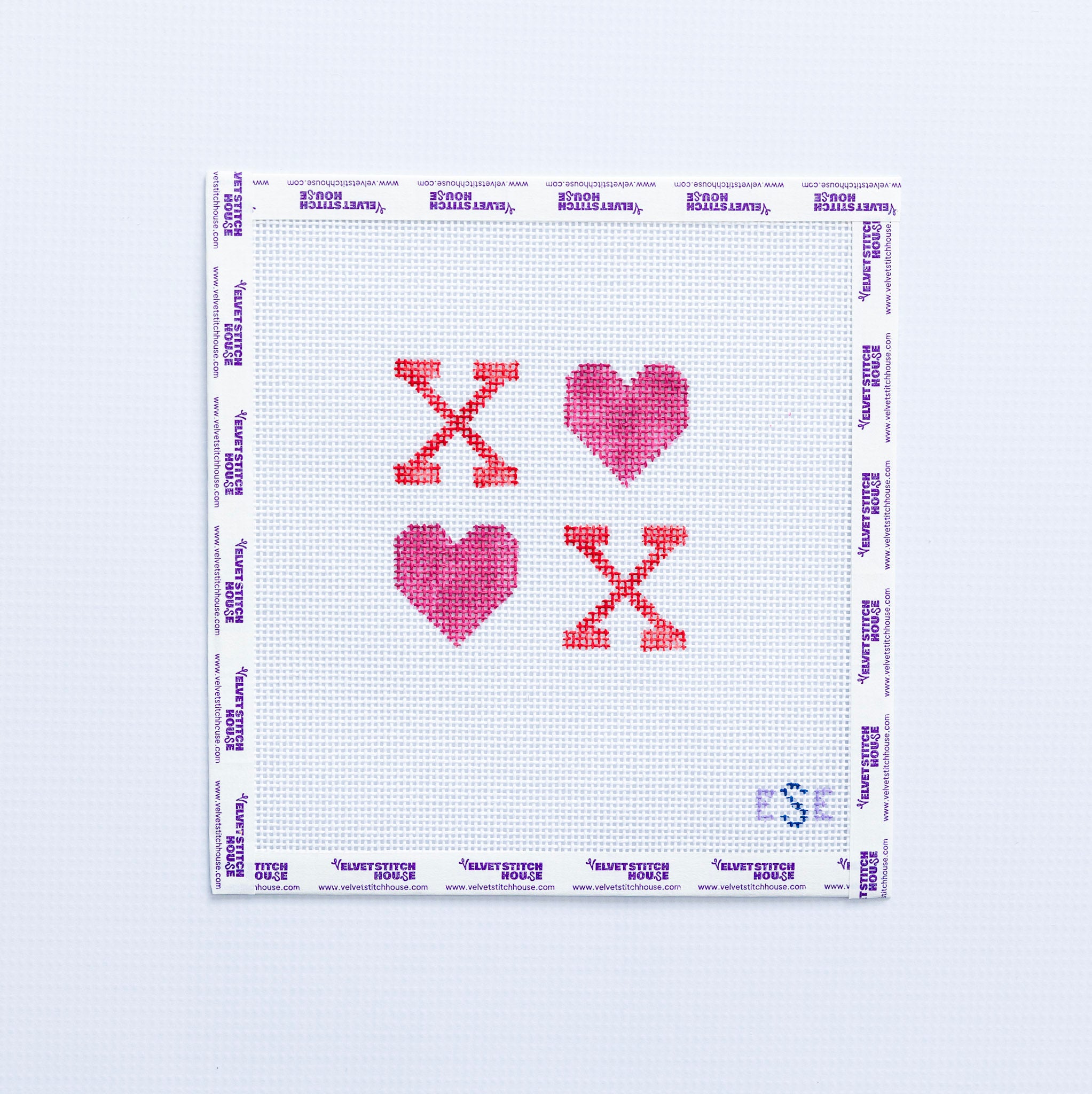 Needlepoint pattern with hearts in pink and red text with 'XO' on a white fabric background